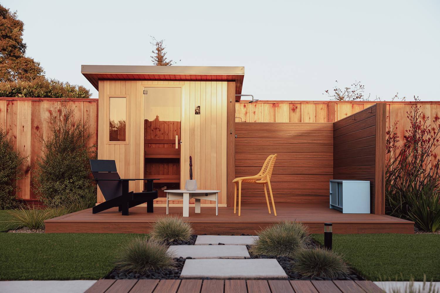 Custom backyard wellness space featuring a sauna, deck, and modern landscape design by K&D Landscaping