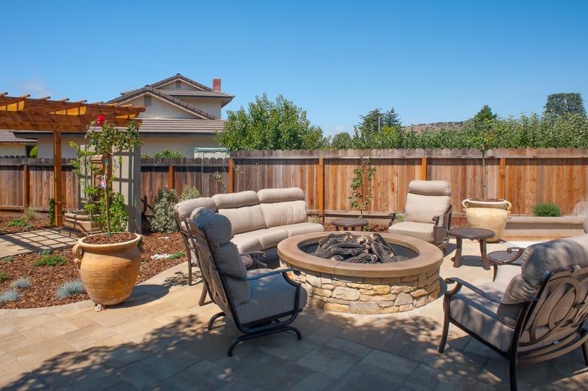 Four beige outdoor furniture seating surrounding a natural stone outdoor fireplace