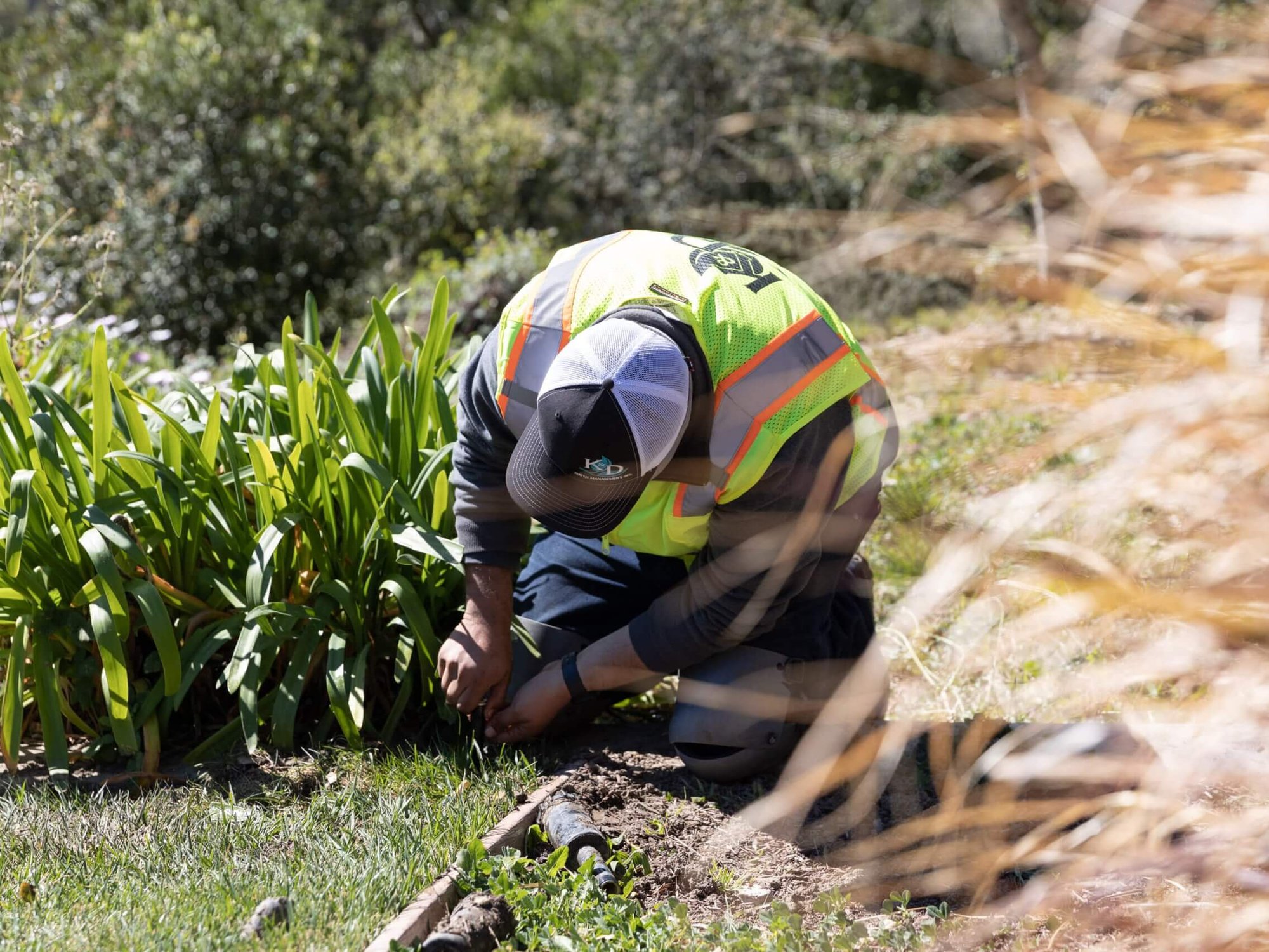 Landscape professional performing irrigation system maintenance and water management services for K&D Landscaping