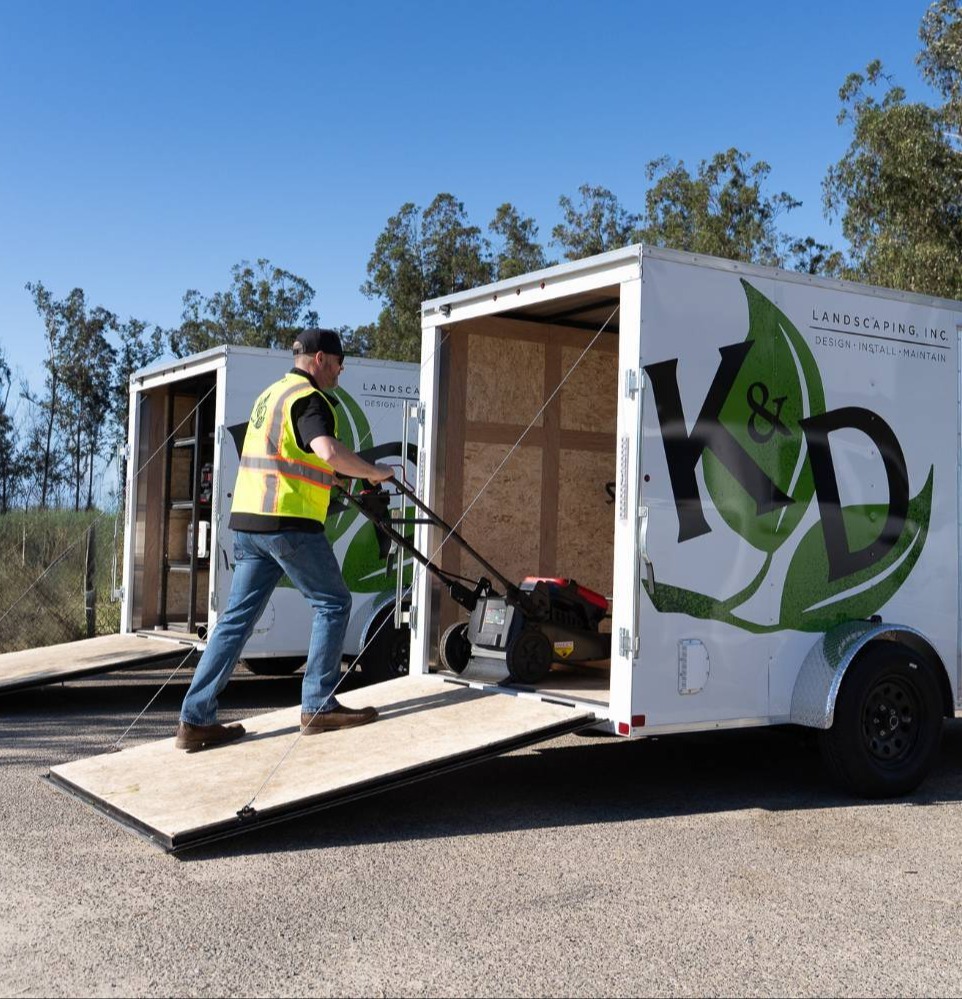 K&D Landscaping team member unloading equipment trailer for landscape maintenance services