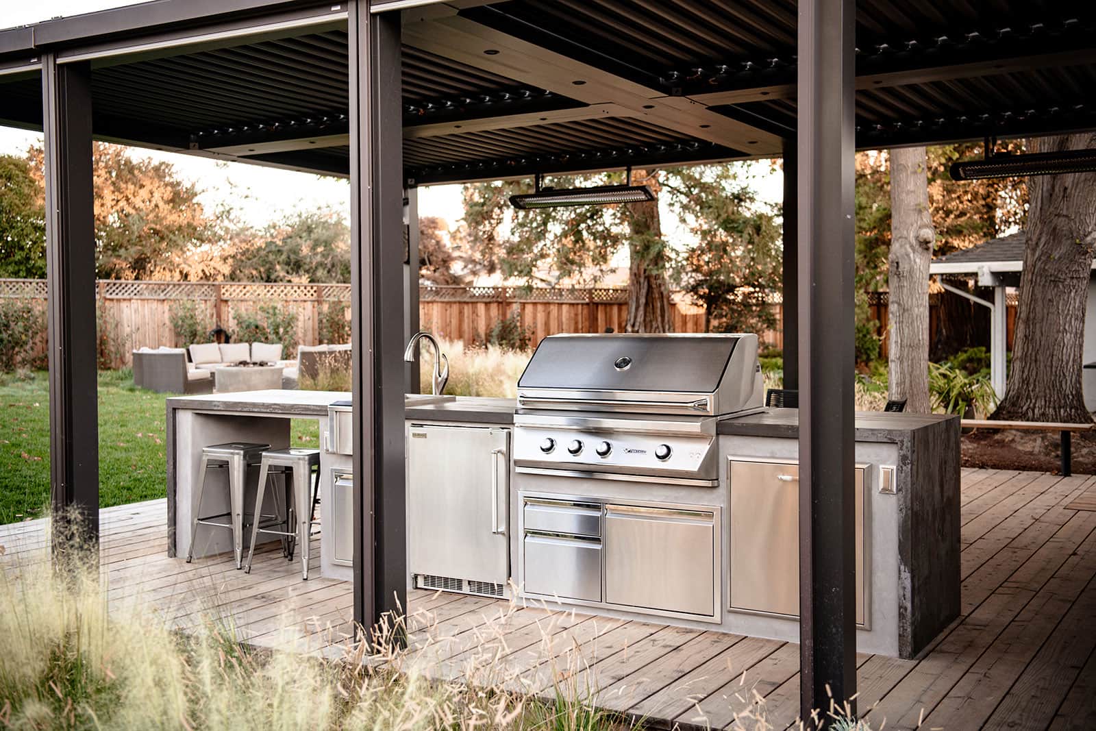 Outdoor kitchen with built-in grill, stone cabinetry, and entertaining area by K&D Landscaping