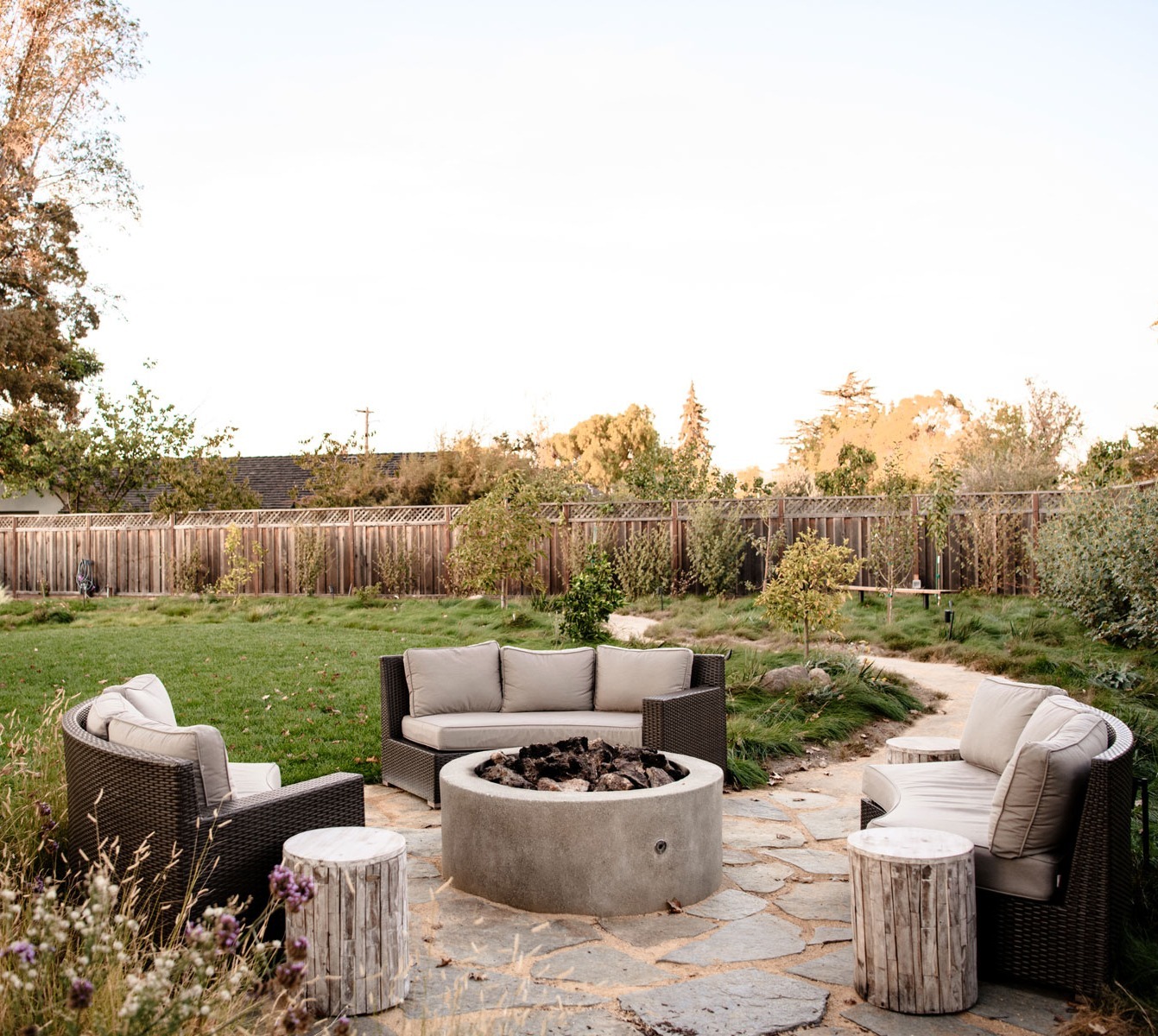 Backyard outdoor living space featuring fire pit seating area, natural stone patio, and landscape design by K&D Landscaping