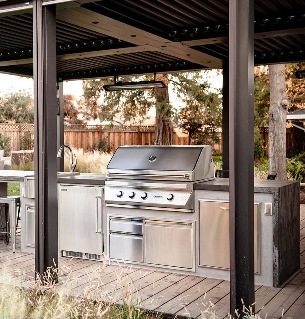 Modern outdoor entertaining space with pergola, kitchen counter, grill, seating, and landscape planting by K&D Landscaping-1