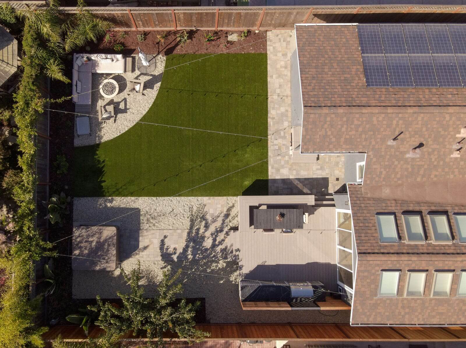 Aerial view of residential landscape design with artificial turf, gravel patios, outdoor dining area, and custom hardscape by K&D Landscaping
