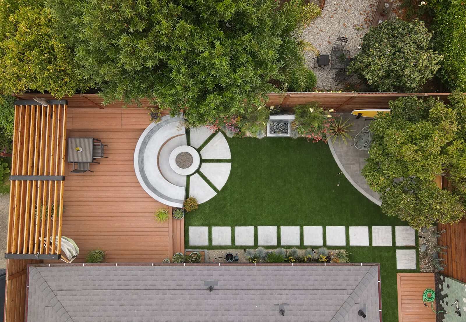 Aerial view of sustainable backyard design with concrete pavers, lawn, TimberTech decking, and custom planting beds by K&D Landscaping