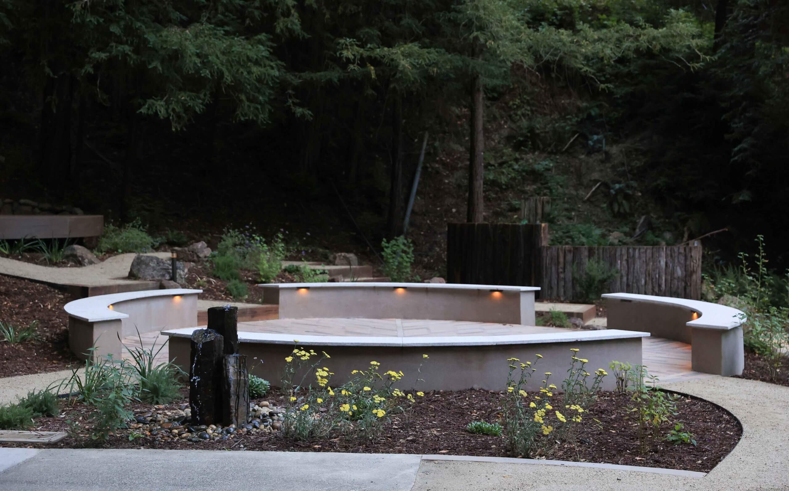Amphitheater-style outdoor seating area with landscape lighting and custom hardscape features by K&D Landscaping