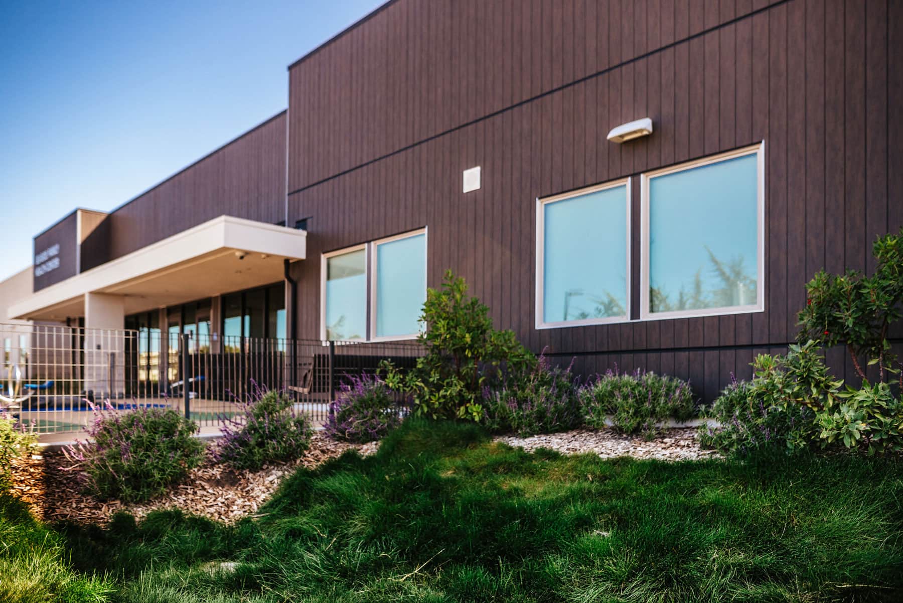 Commercial landscape building exterior with native plantings, mulch beds, blooming perennial flowers completed by K&D Landscaping