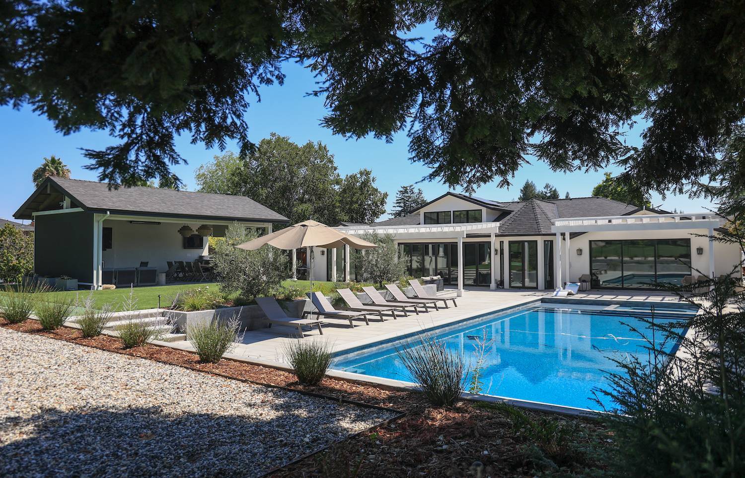 Contemporary residential backyard with custom pool and outdoor living space by K&D Landscaping