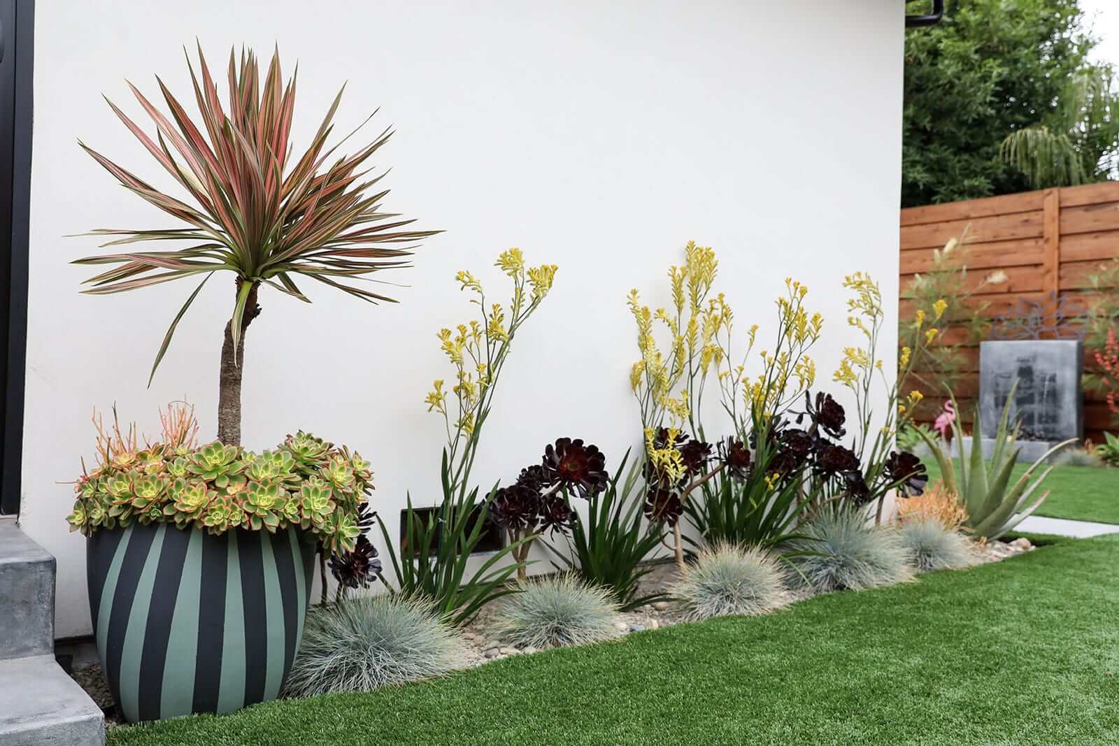 Custom concrete bench with sloped backrest and surrounding plantings by K&D Landscaping