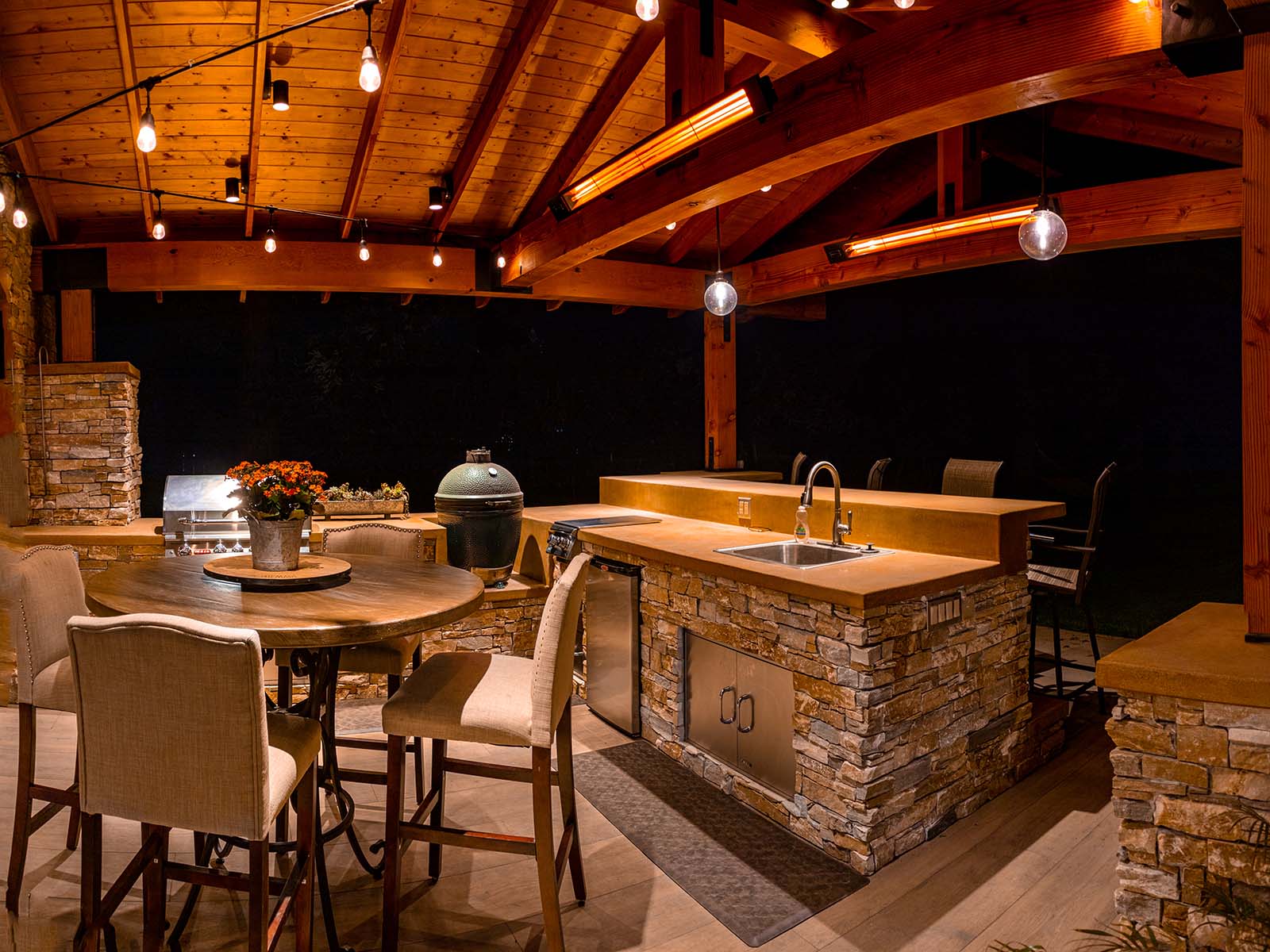 Custom outdoor bar and kitchen with built-in grill, sink, and entertainment area by K&D Landscaping