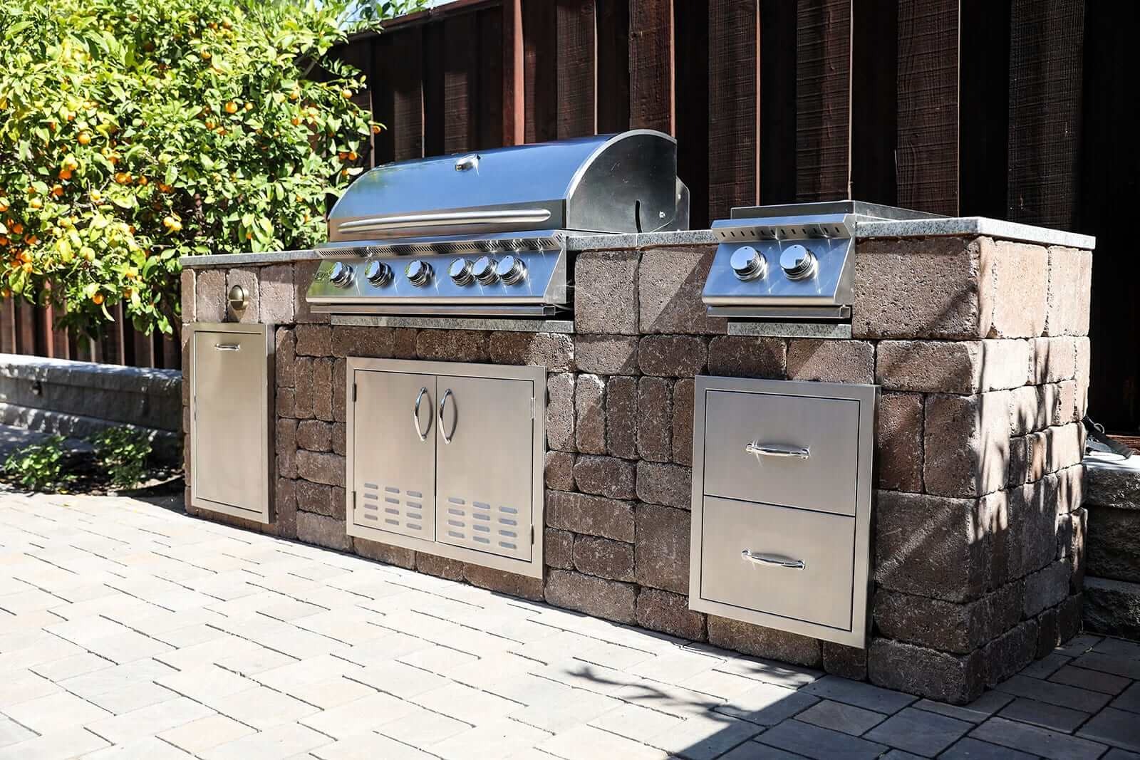 Custom outdoor kitchen integrated into a residential landscape design by K&D Landscaping