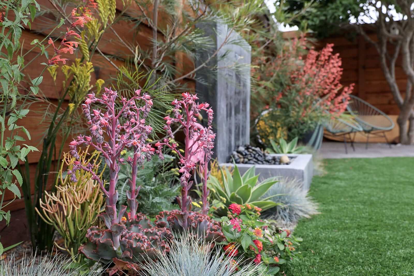 Decorative planting beds surrounding custom concrete hardscape by K&D Landscaping