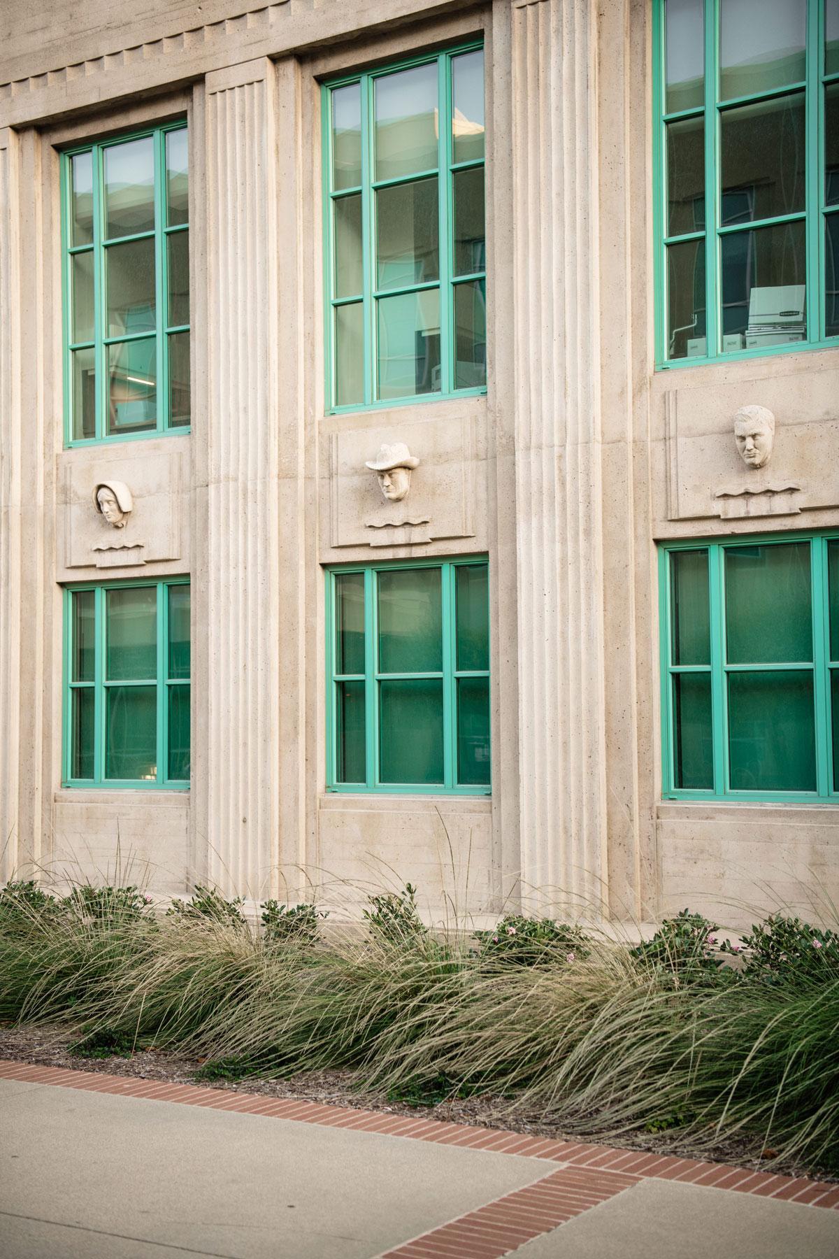 Government building facade with turquoise-frame windows, stone columns, and ornamental grass plantings designed by K&D Landscaping