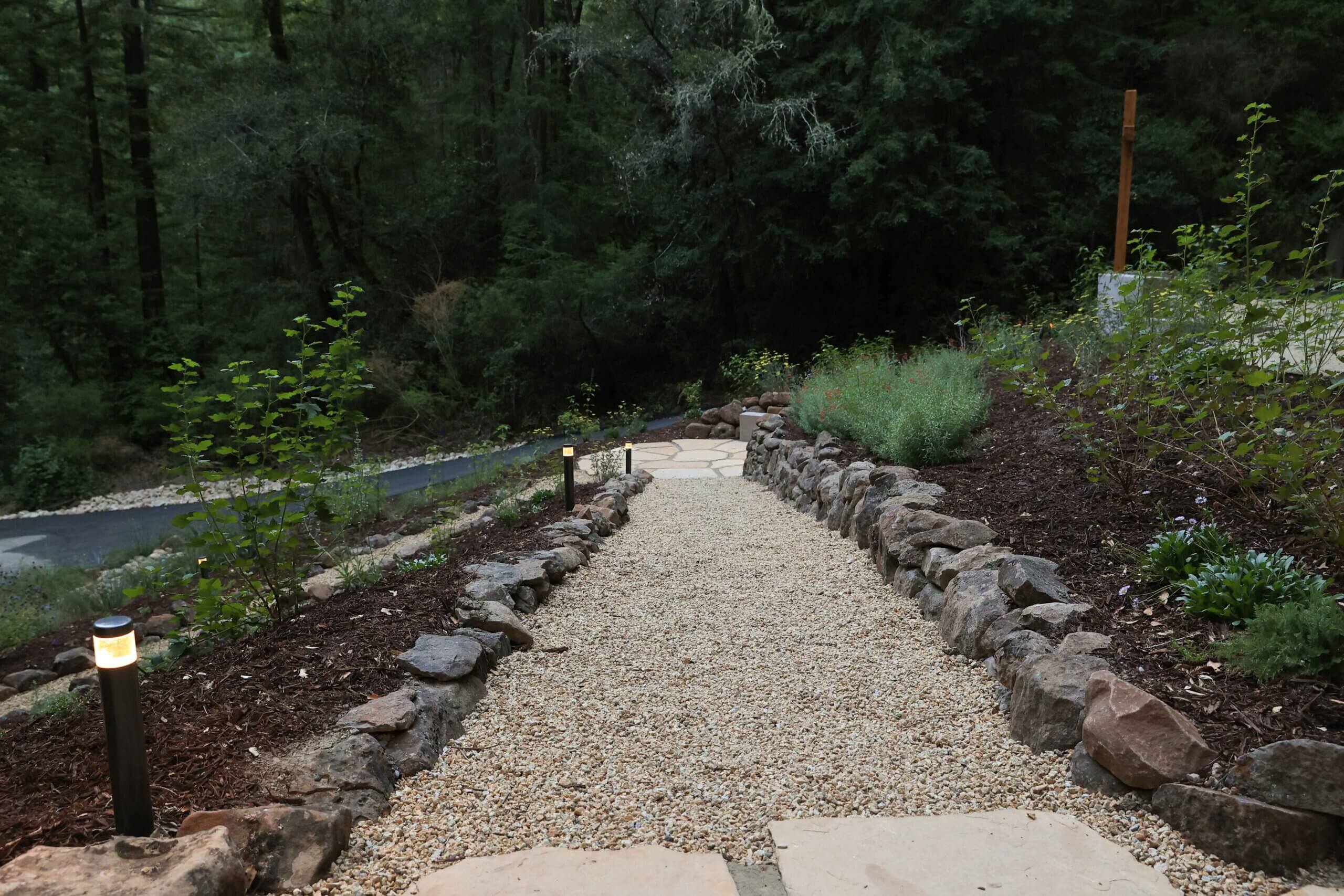 Gravel pathway bordered by natural stone and native plantings in a woodland landscape by K&D Landscaping