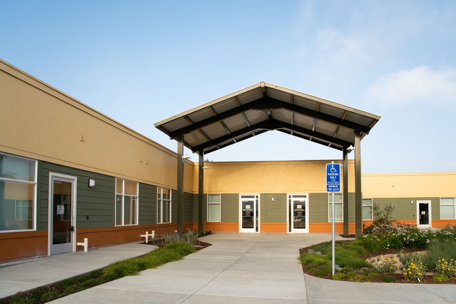 K&D Landscaping building facade landscape with butterfly art mural, foreground planting beds, and gravel design