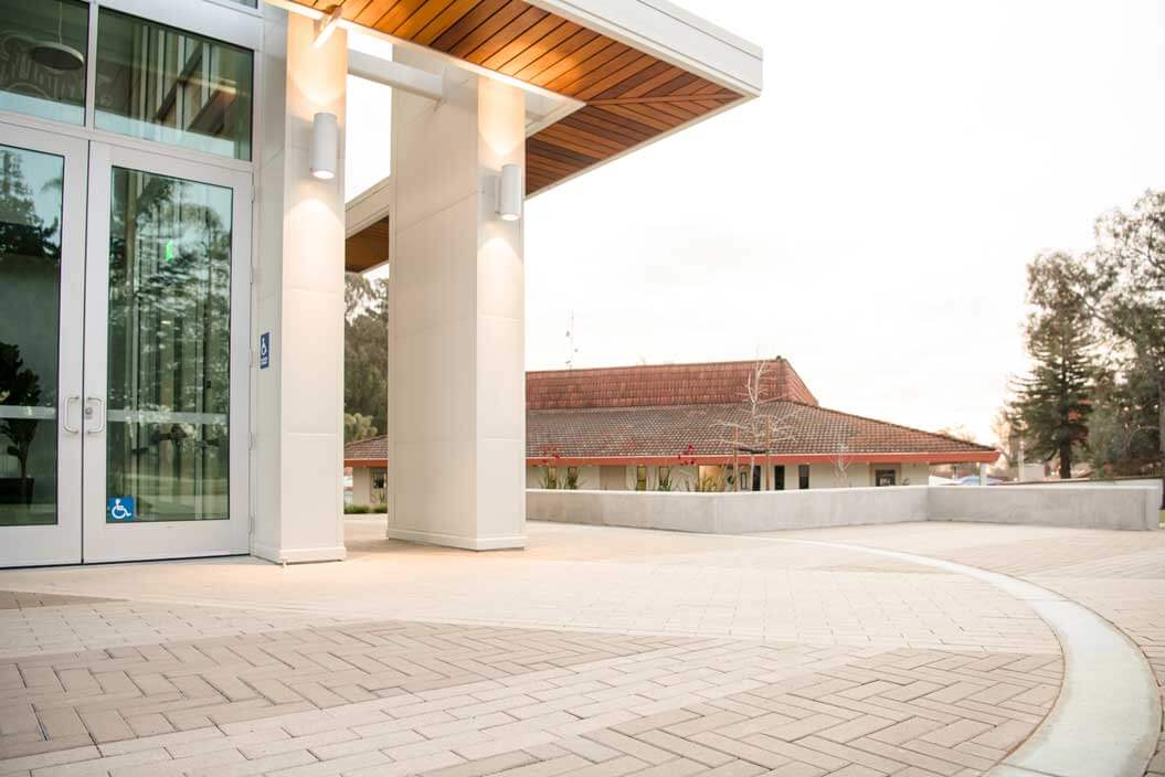 K&D Landscaping covered building entry with a cedar soffit and sweeping herringbone paver plaza