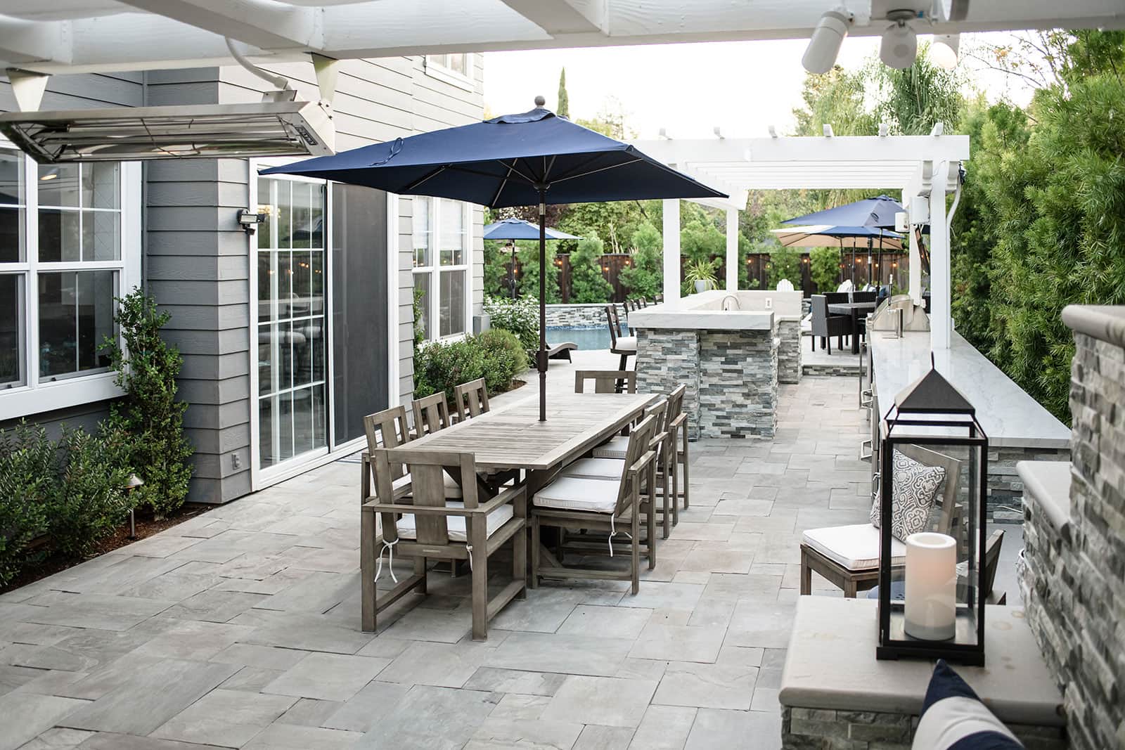 K&D Landscaping covered patio lounge with outdoor furniture, stone accents, and landscape lighting