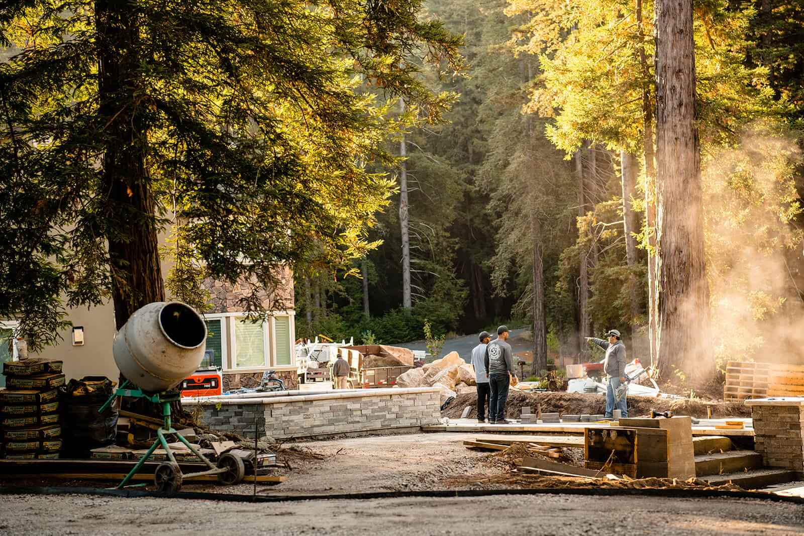K&D Landscaping crew installing a stacked-stone wall during construction with a cement mixer on site