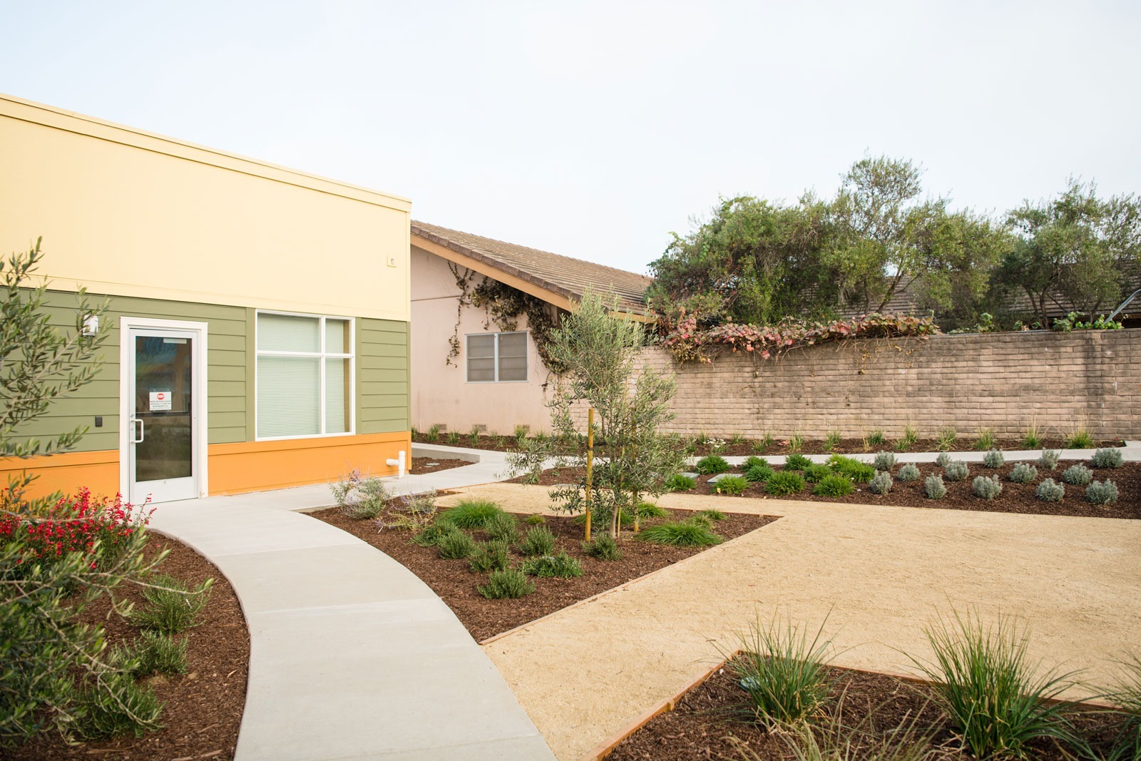 K&D Landscaping curved concrete pathway landscape with ornamental shrubs, mulch beds, and site connectivity