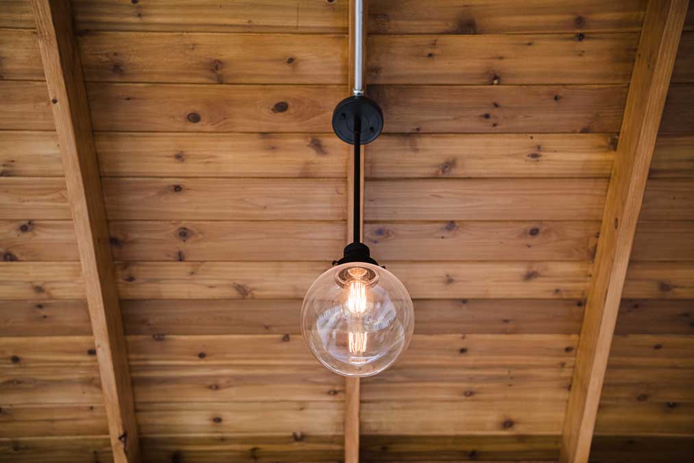 K&D Landscaping globe pendant light hanging from a cedar tongue-and-groove ceiling