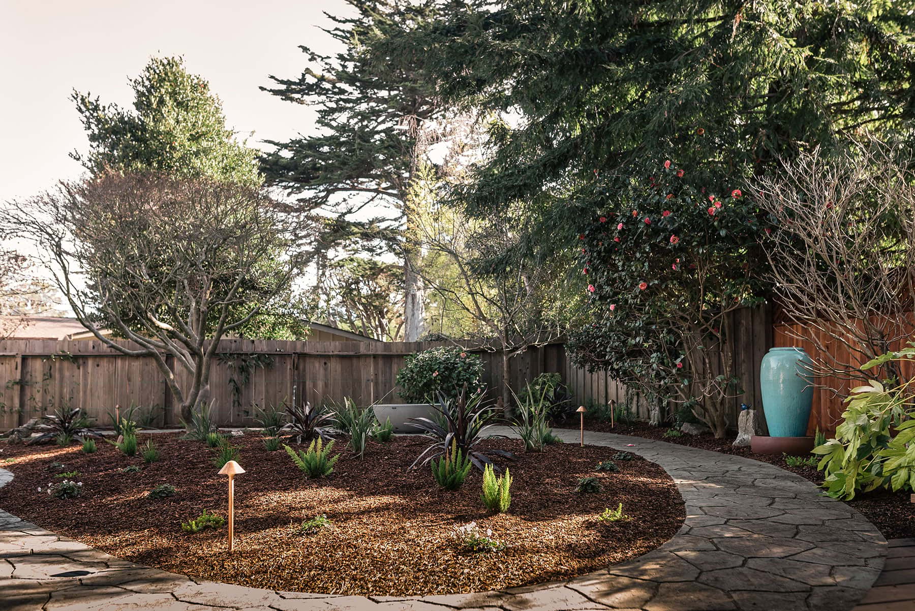 K&D Landscaping landscape design with mulch beds, native plantings, pathways, blue pottery vessels, and shade trees
