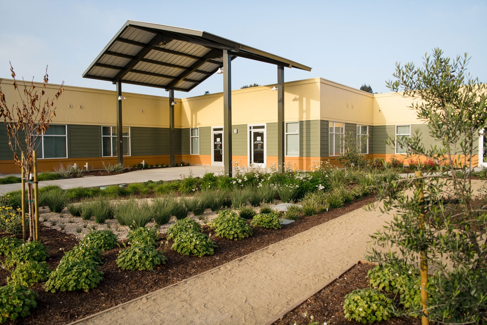 K&D Landscaping metal shade structure with surrounding landscape installation, gravel beds, and native plantings