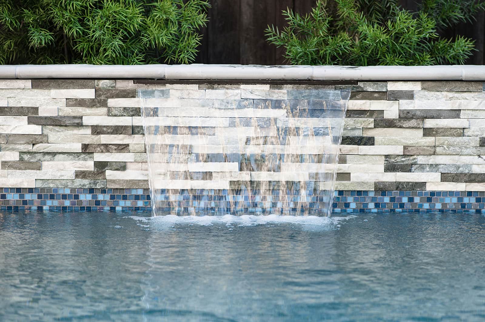 K&D Landscaping outdoor kitchen bar with pergola cover, stone veneer, and bar seating