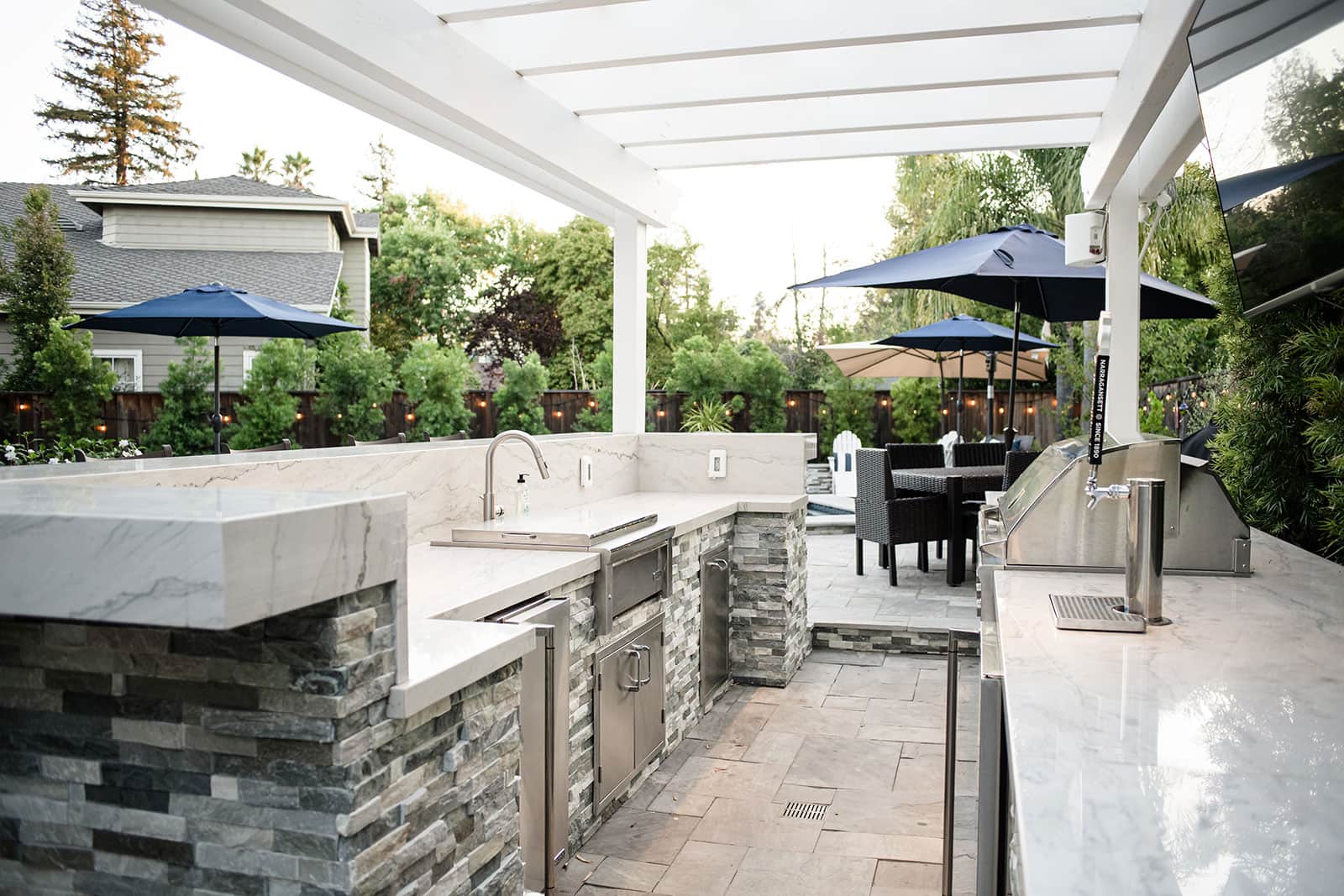 K&D Landscaping outdoor kitchen with marble waterfall counters, stainless appliances and a kegerator