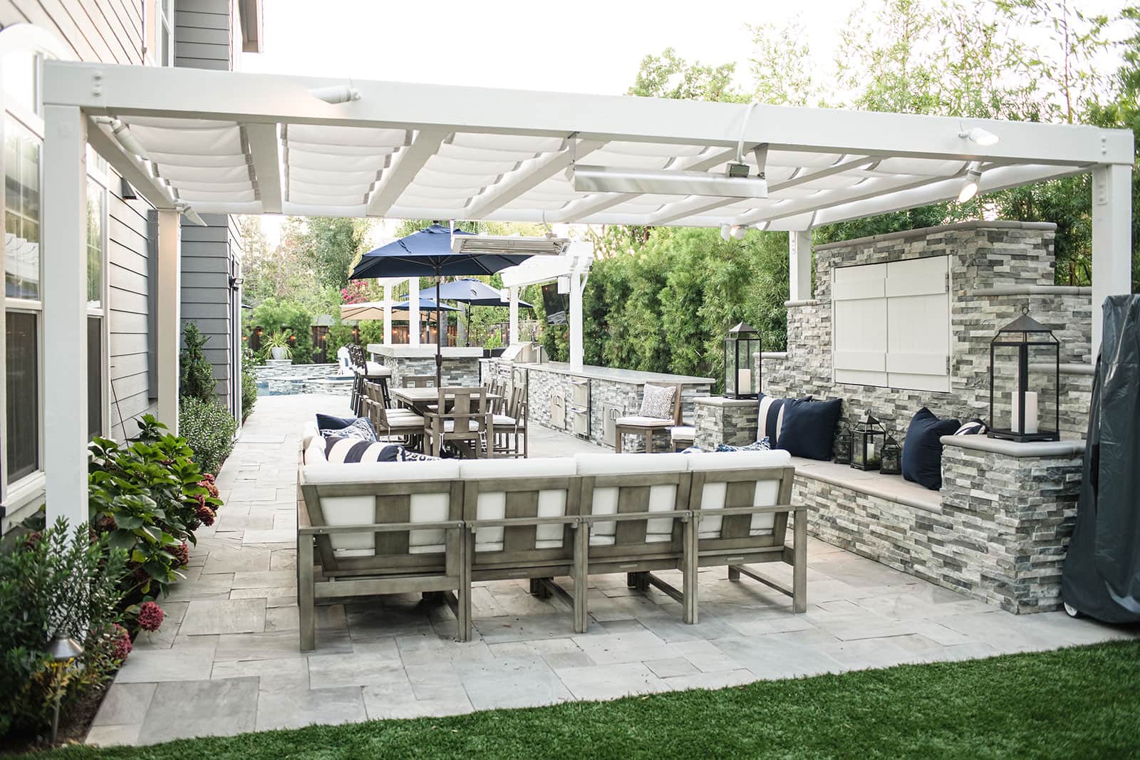 K&D Landscaping swimming pool and spa with stone water features, privacy screening, and patio