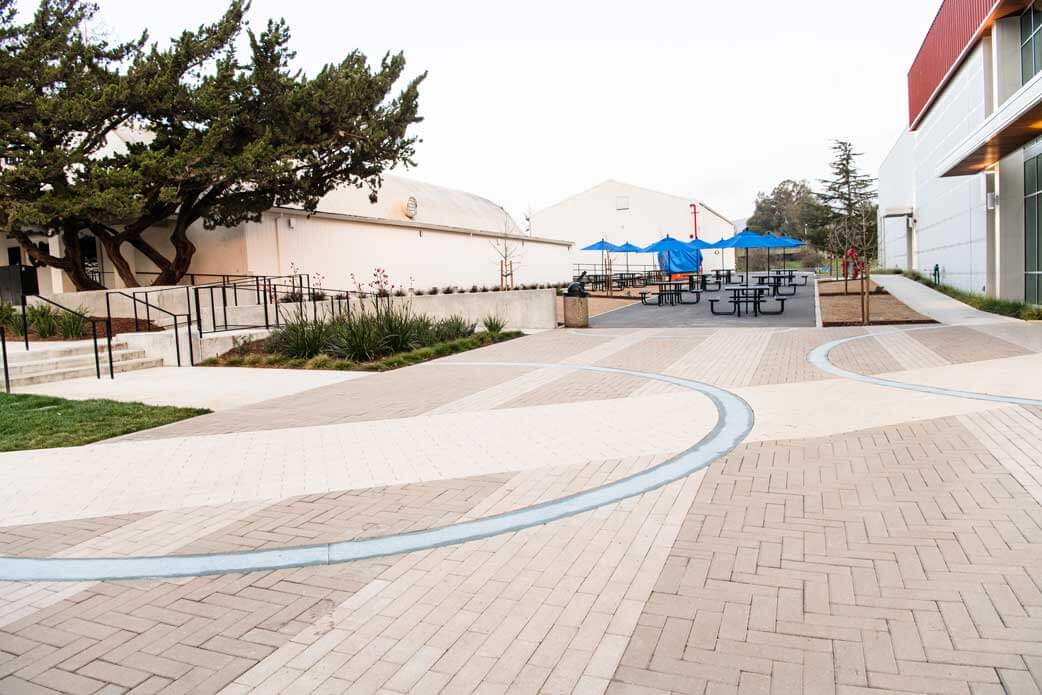 K&D Landscaping two-tone paver plaza with curved banding leading to a shaded lunch terrace