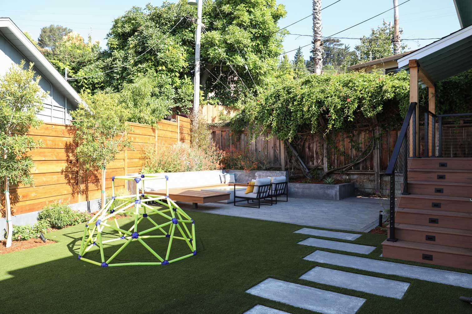 Modern backyard design featuring artificial turf, custom fencing, and outdoor seating by K&D Landscaping