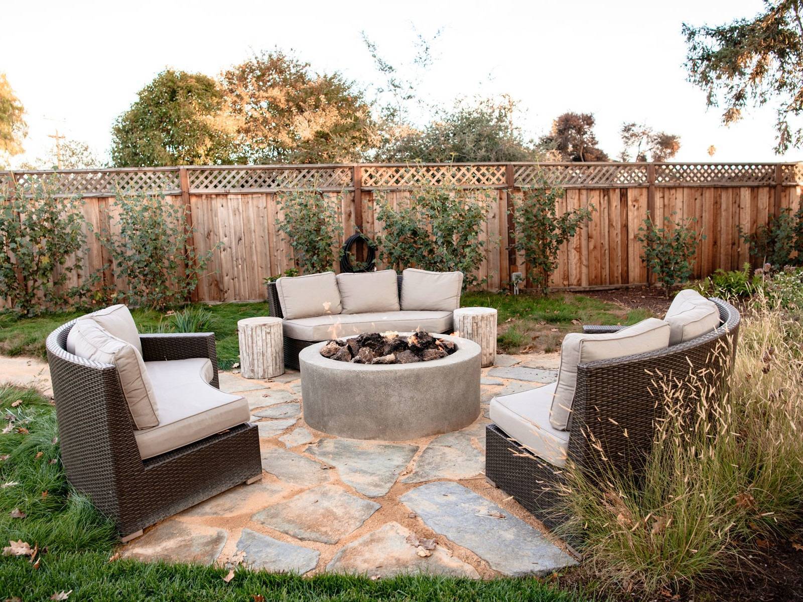 Natural stone fire pit patio with wicker furniture, drought-tolerant planting, and climbing ivy installed by K&D Landscaping