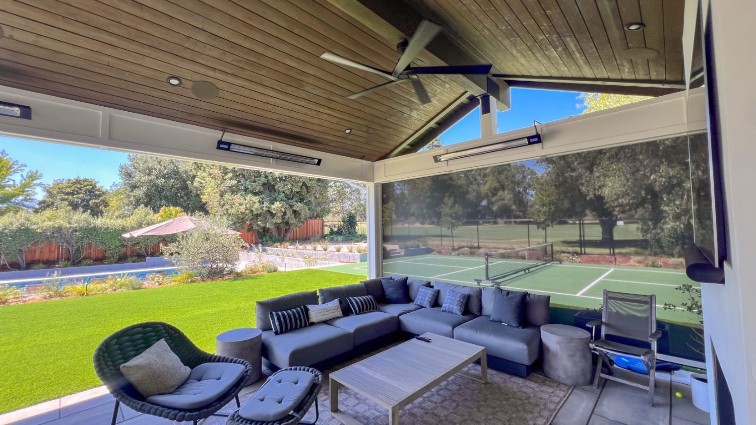 Outdoor kitchen and dining area connected to poolside gathering spaces by K&D Landscaping
