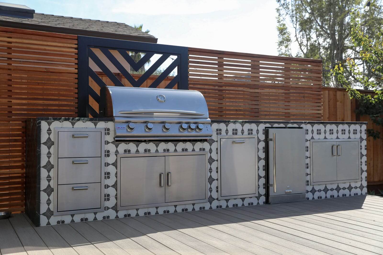 Outdoor living space with custom kitchen, fire feature, and seating areas by K&D Landscaping