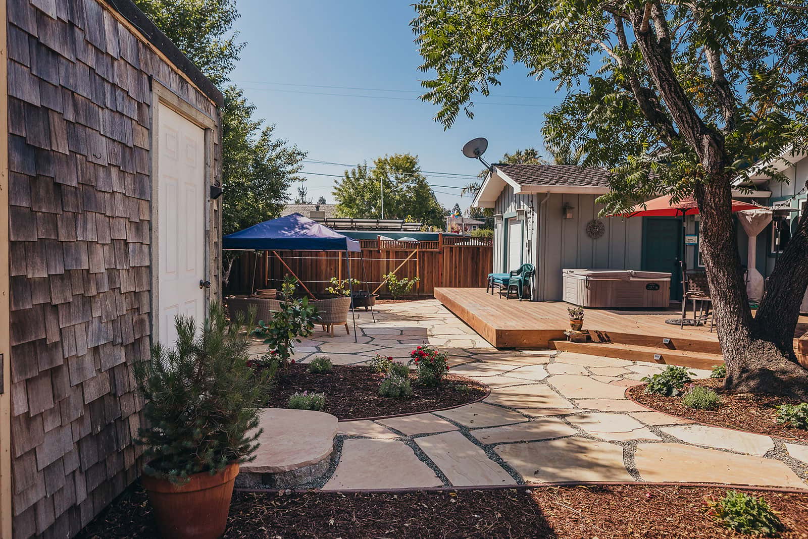 Patio garden with vibrant red rose plantings, flowering shrubs, shaded entertaining area, and landscape beds by K&D Landscaping