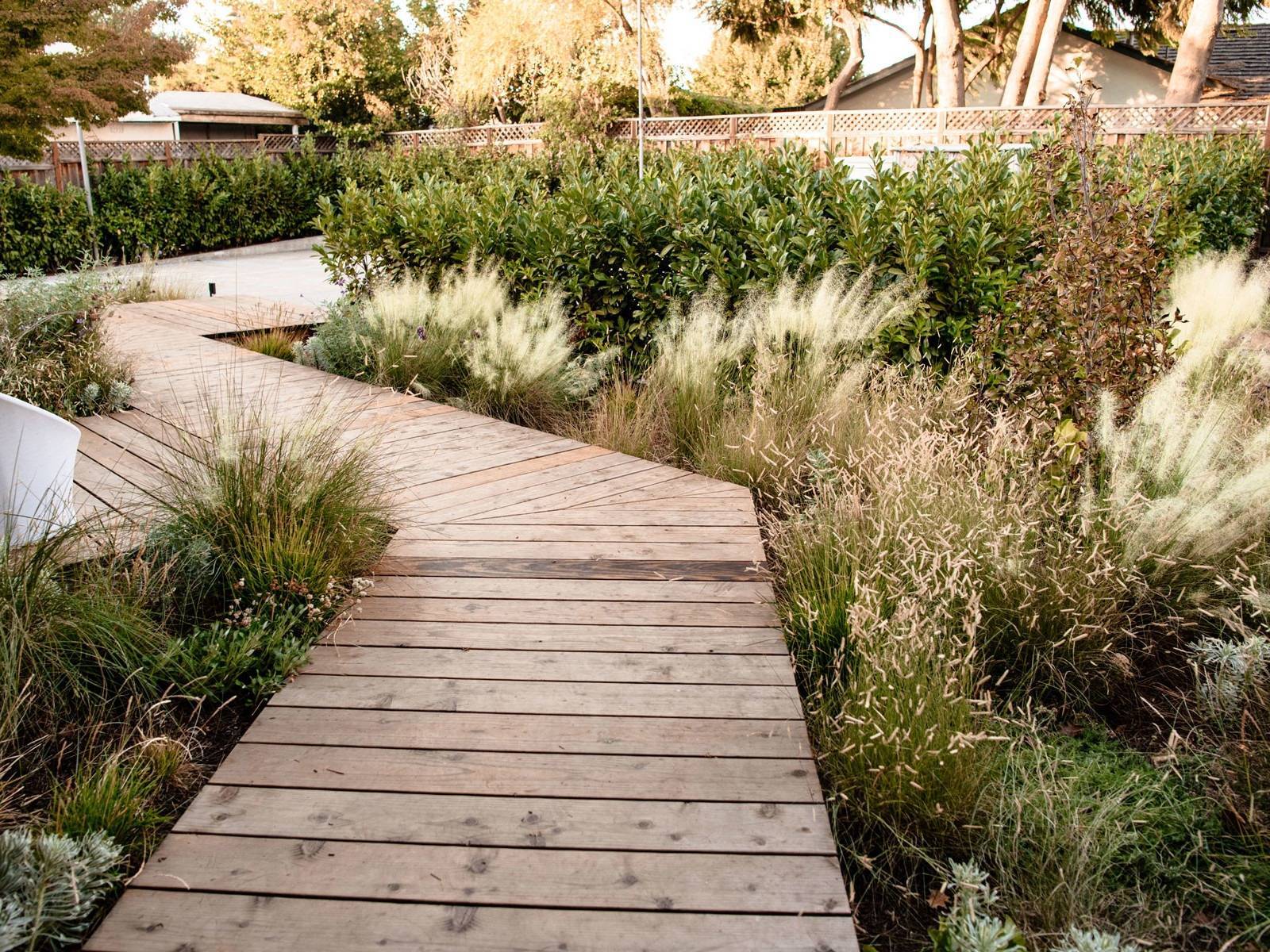 Residential backyard landscape with stone fire pit, wicker furnishings, ornamental grasses, and custom planting beds by K&D Landscaping