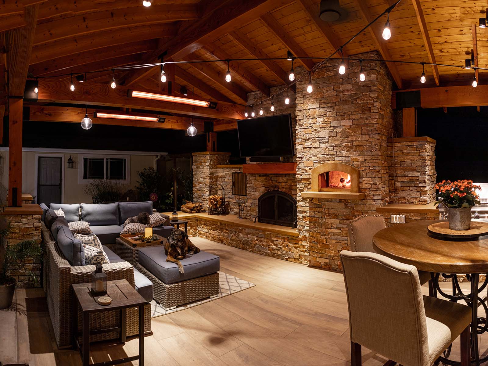 Residential outdoor living space featuring fireplace, television, dining area, and custom pavilion by K&D Landscaping