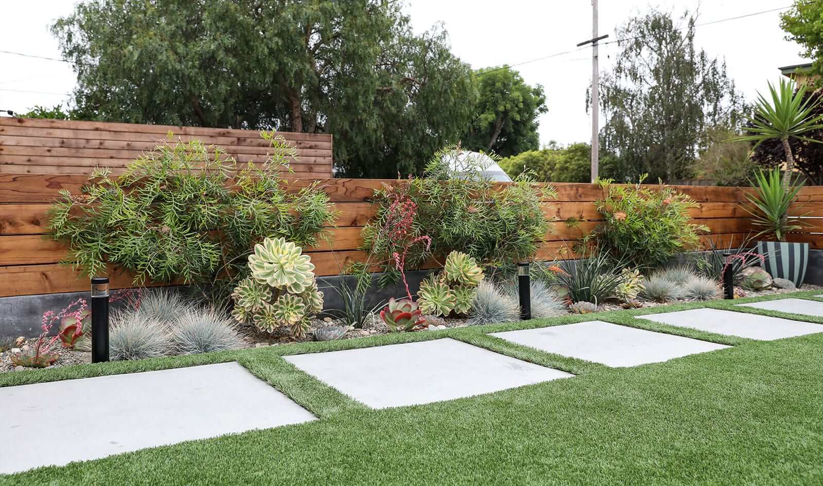 Smooth concrete stepping stone pathway through a custom landscape by K&D Landscaping