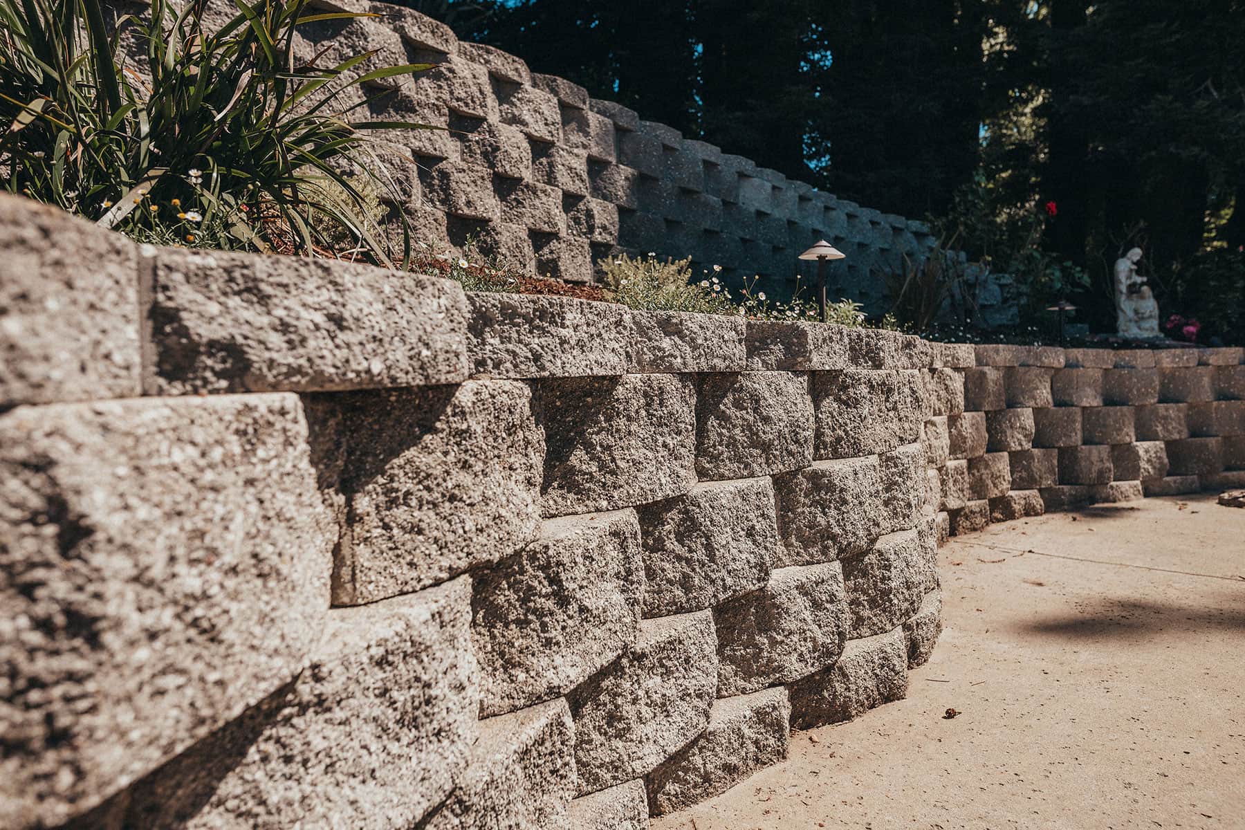 Stacked ledge stone retaining wall with ornamental planting and soil preparation installed by K&D Landscaping