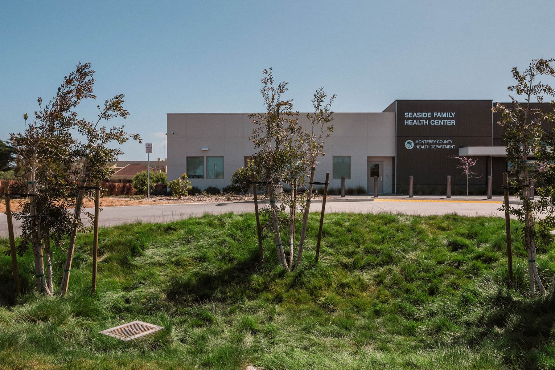 Wide commercial landscape with native plantings, ornamental grasses, fencing, and medical facility setting by K&D Landscaping