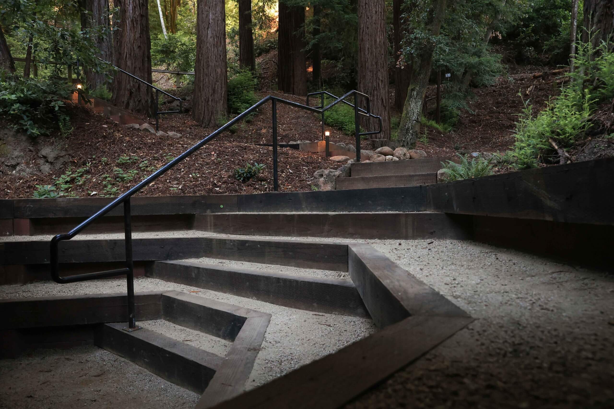 Woodland landscape featuring retaining walls, pathways, and gathering areas by K&D Landscaping